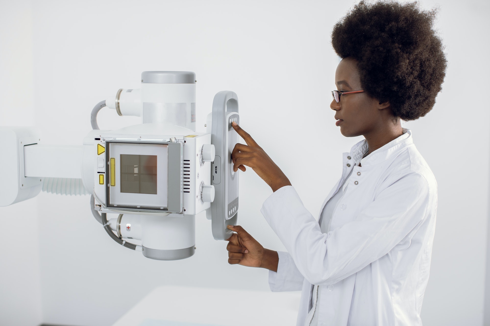 Close up portrait of young African American lady doctor working with modern X-ray machine for