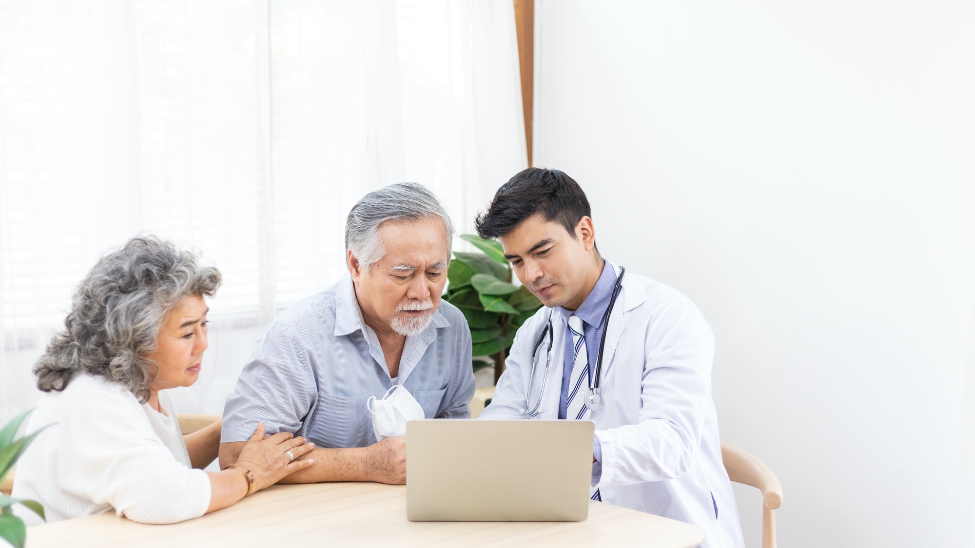 Doctor using computer discussing test result and diagnosis to Asian senior man